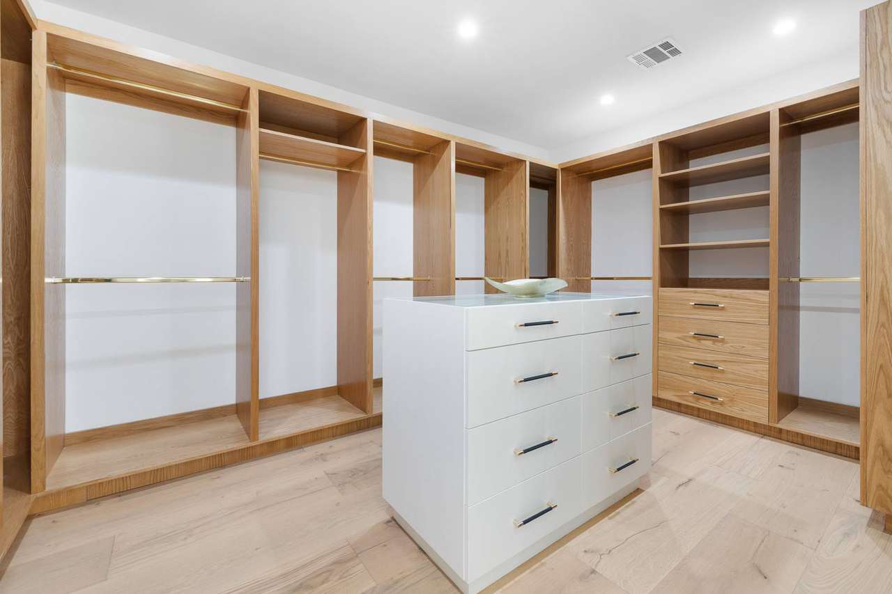 Custom walk-in closet with natural wood storage and center island by Millwork USA