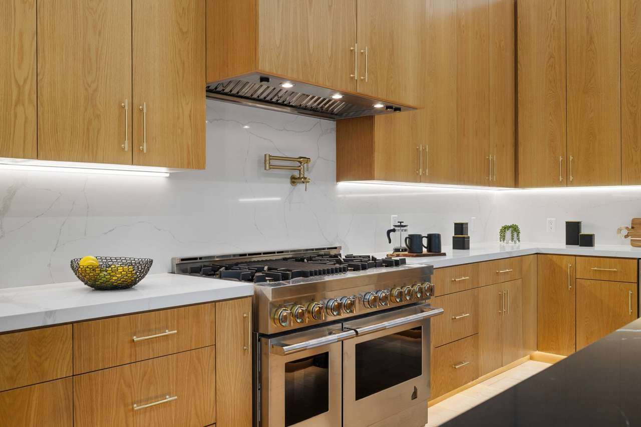 Custom kitchen range detail with natural wood cabinetry and stone backsplash