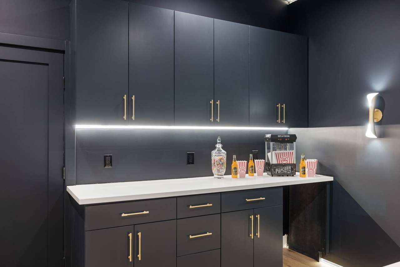 Dark media room custom cabinetry with brass hardware and integrated lighting